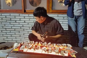 Iemand barbecuet oesters op een grill.