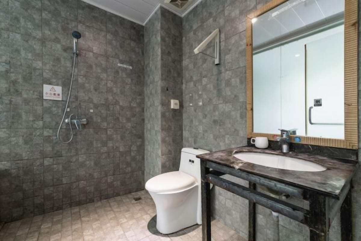 Een badkamer met een marmeren wastafel, een spiegel en een douche.