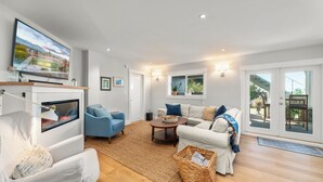 A spacious living room with a fireplace, comfortable seating, and a large TV screen.