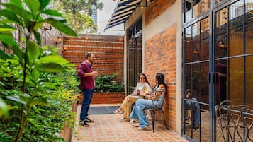 Uma área de estar externa com parede de tijolos, porta de vidro e piso estampado.