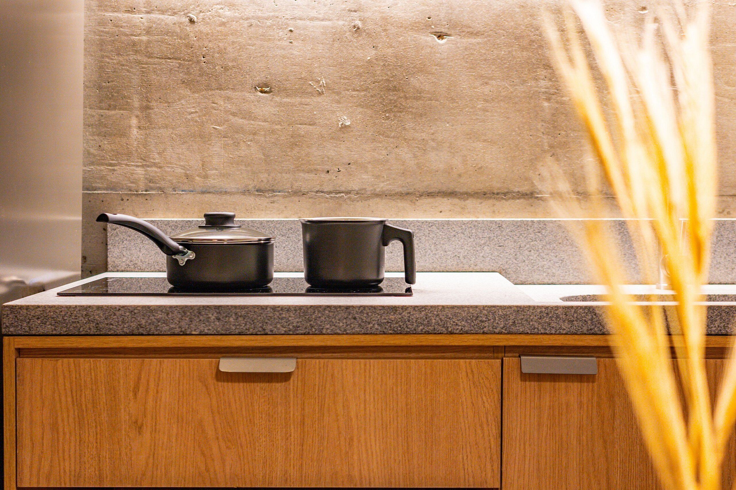 Una cocina con encimera de granito, un mueble de madera y un lavamanos de acero inoxidable.