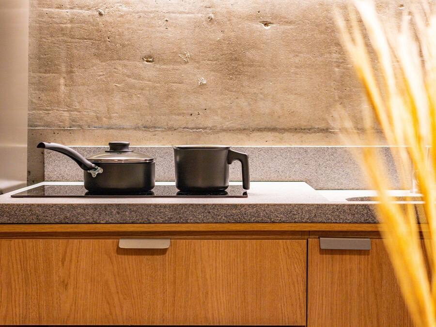 Una cocina con encimera de granito, un mueble de madera y un lavamanos de acero inoxidable.