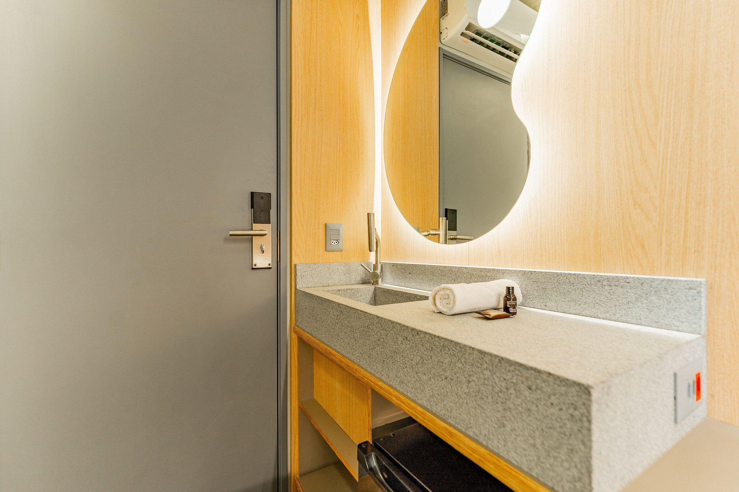 A modern bathroom with a grey granite countertop, a round mirror, and a towel.