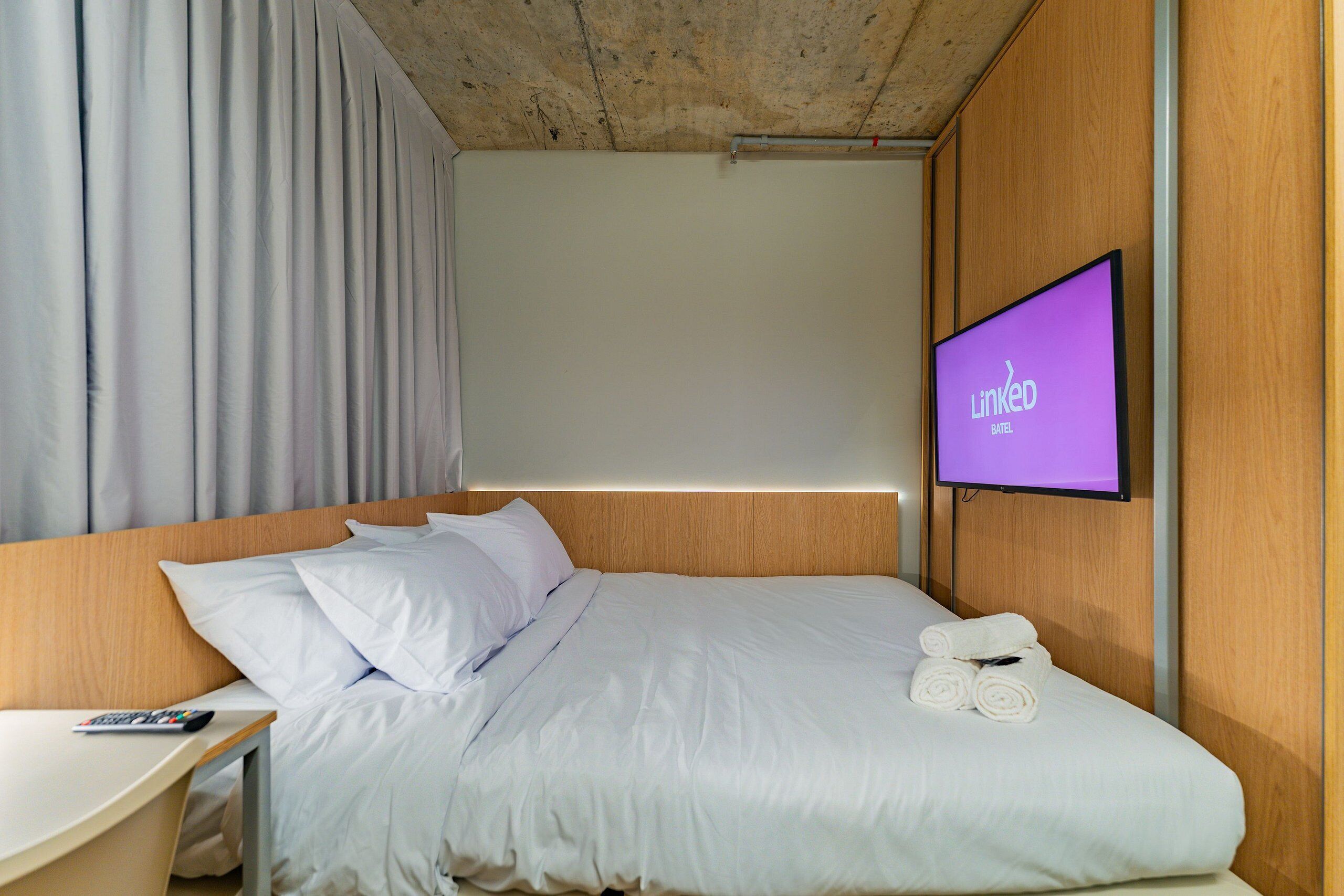 Een hotelkamer met een bed, een tv aan de muur, een bureau en een stoel.