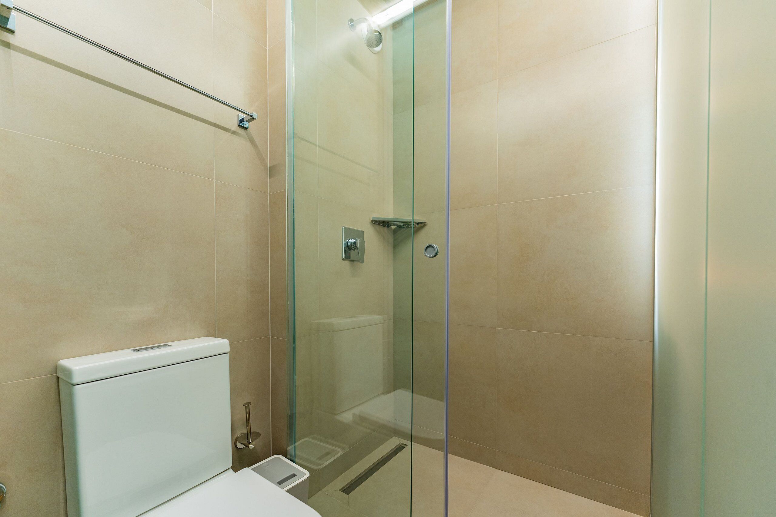 A modern bathroom with a glass-enclosed shower, a white toilet, and a glass shower door.