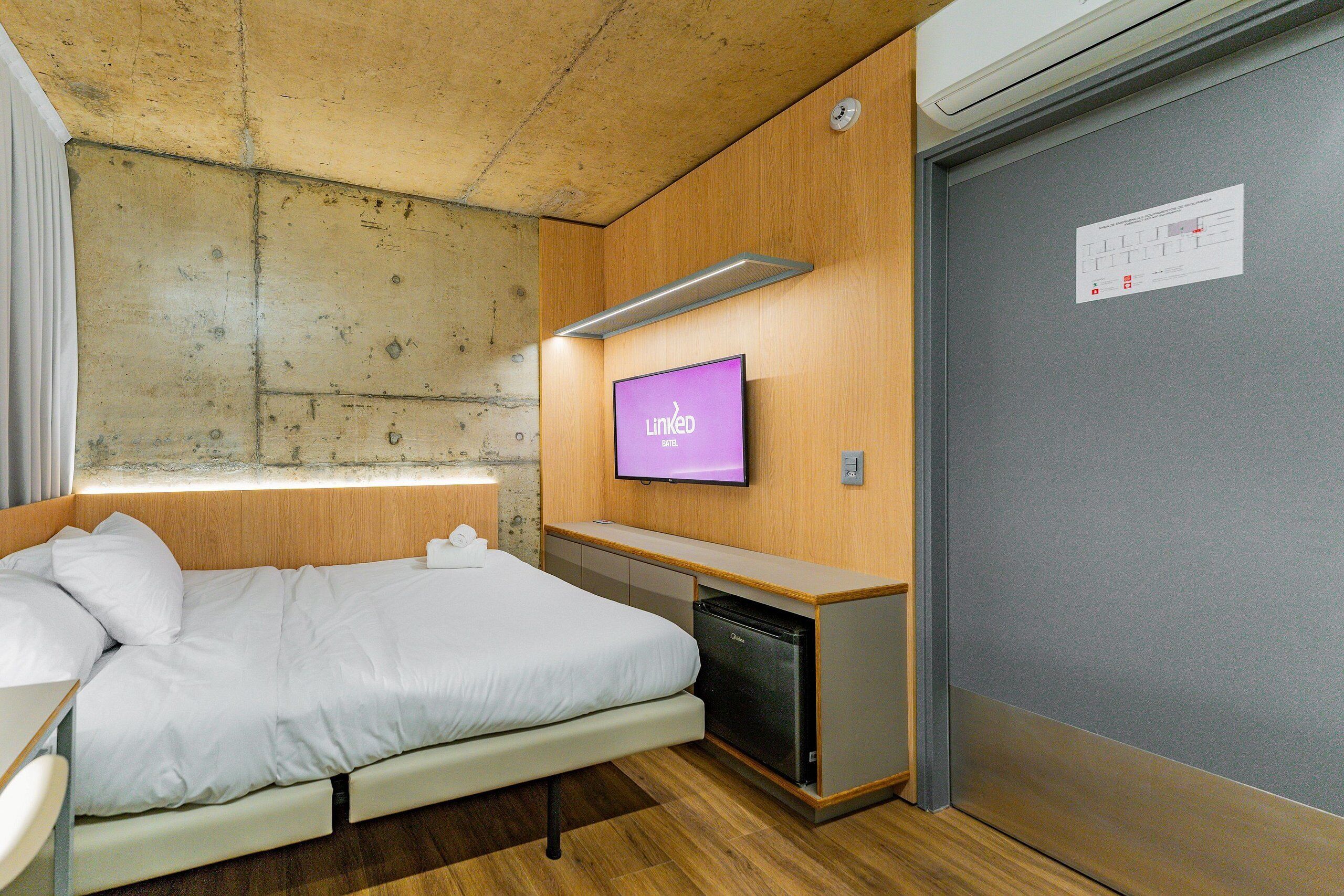Habitación de hotel con cama, escritorio pequeño, televisión y minibar.