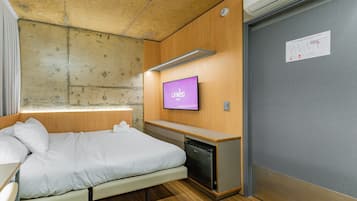 Habitación de hotel con cama, escritorio pequeño, televisión y minibar.