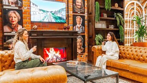 A cozy living room with leather sofas, a fireplace, and a television. - Linked Batel by Xtay (Curitiba)