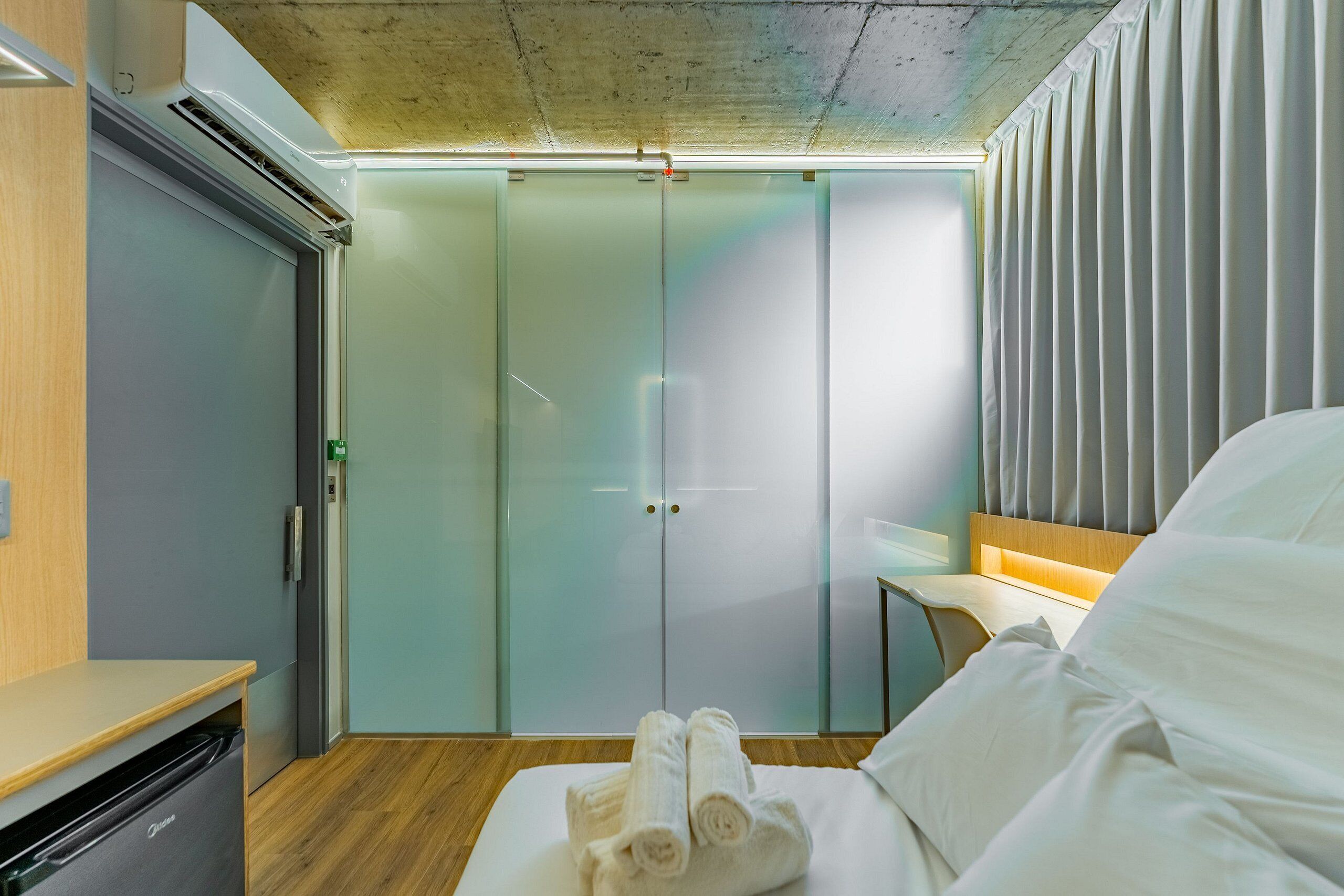 A hotel room with a bed, a desk, a wardrobe, and a bathroom.