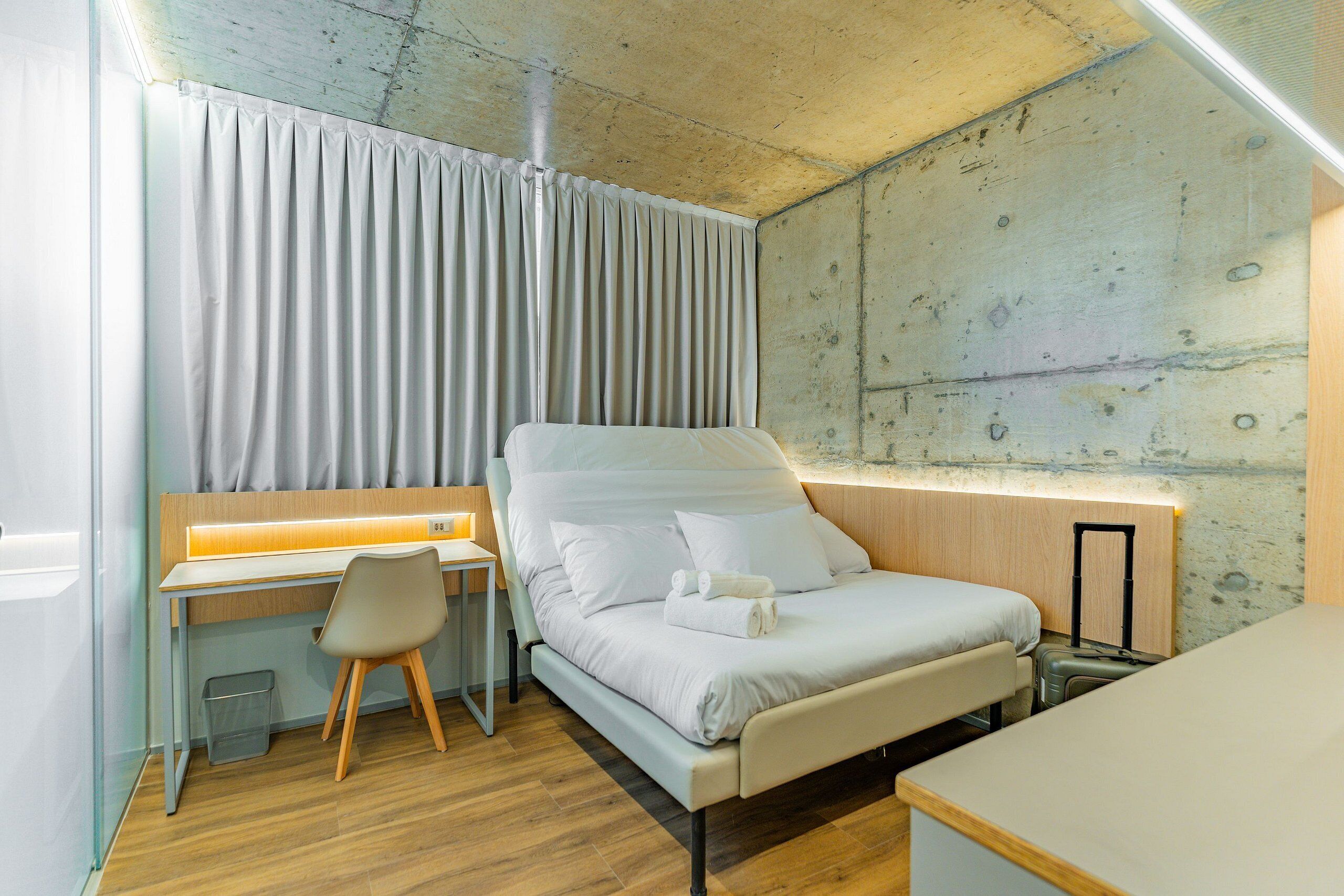 Habitación de hotel pequeña con cama, escritorio y silla.