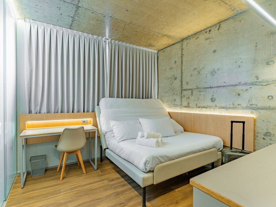 Habitación de hotel pequeña con cama, escritorio y silla.