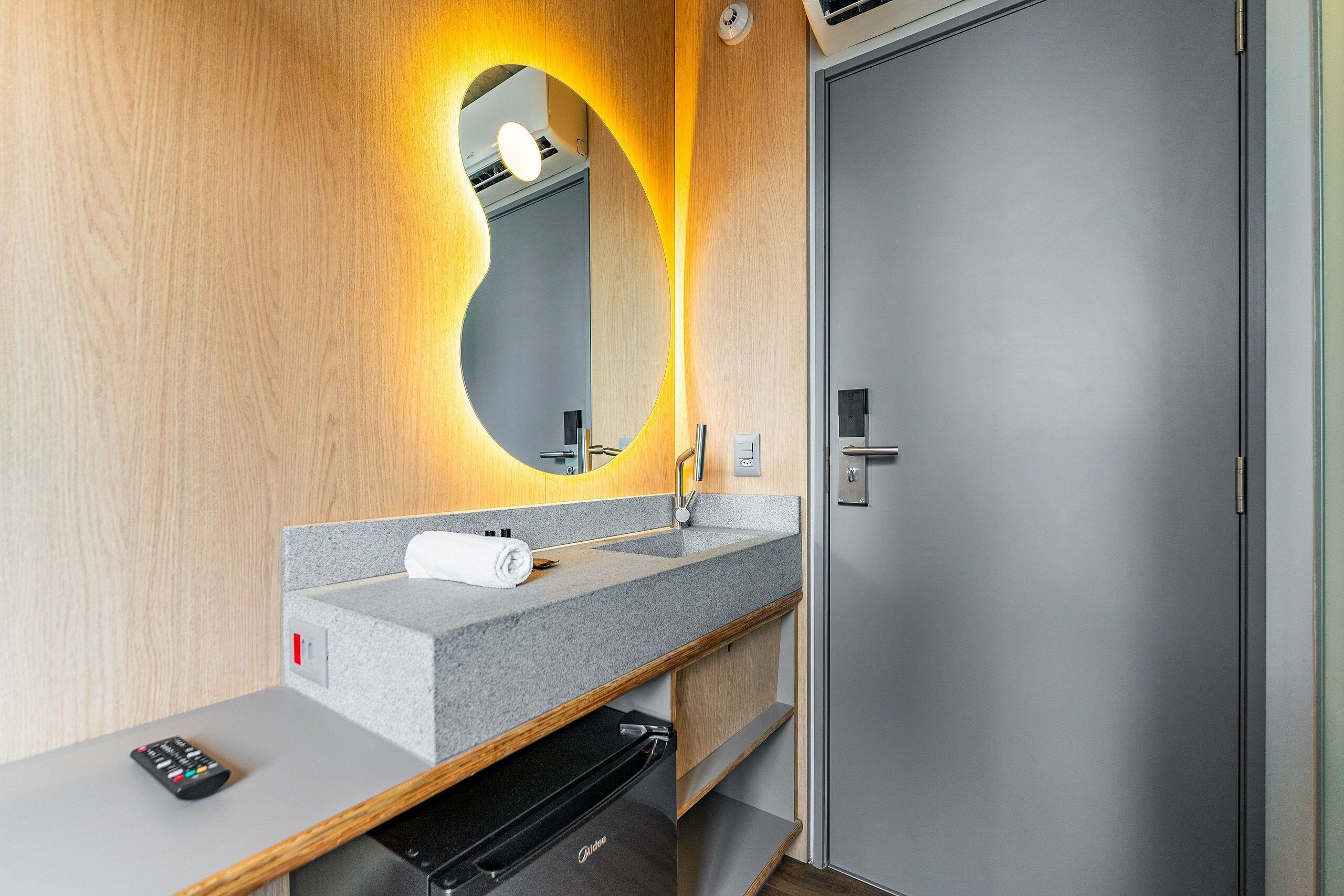 Un baño moderno con encimera de granito, espejo con marco circular, una toalla y electrodoméstico negro.