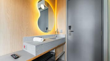 Un baño moderno con encimera de granito, espejo con marco circular, una toalla y electrodoméstico negro.