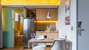 A compact kitchen with a refrigerator, wooden cabinets, and a dining area with a table and chairs. - Linked Batel by Xtay (Curitiba)