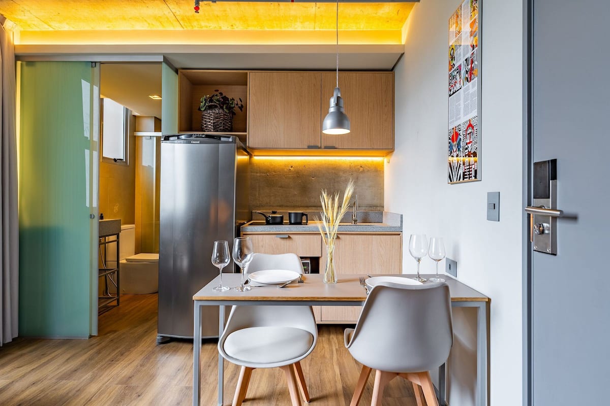 A compact kitchen with a refrigerator, wooden cabinets, and a dining area with a table and chairs.