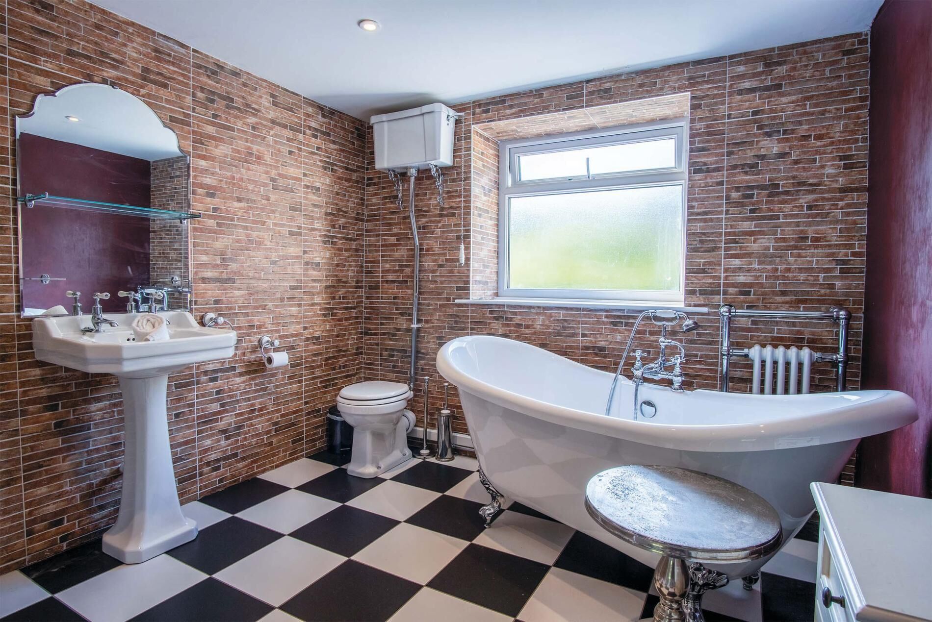 A bathroom with a freestanding bathtub, a pedestal sink, and a toilet.