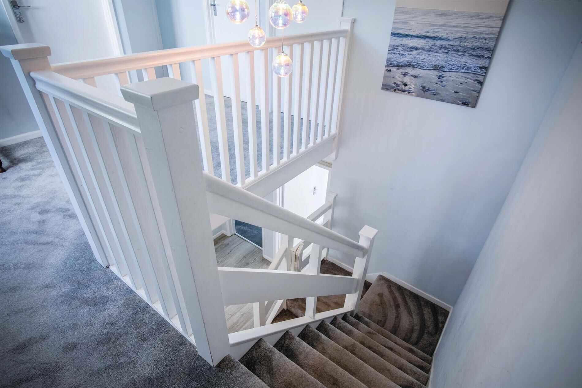 A white wooden staircase with a handrail, carpeted steps, and a view of the outdoors through a window.
