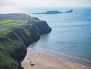 A coastal landscape with a beach, cliffs, and a distant island.