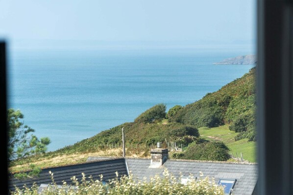 A coastal view with a house on a hill overlooking the sea.
