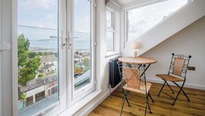 Una habitación con ventanas amplias, vistas al mar, una mesa redonda y dos sillas de mimbre.