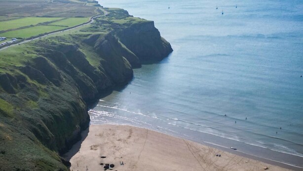 A coastal landscape with a beach, cliffs, and a distant island.