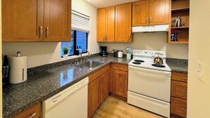 A kitchen with wooden cabinets, a white stove, a dishwasher, and a granite countertop. - Cedar Heights w sauna/bonfire (Lynnwood)