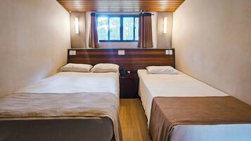 Una habitación con dos camas, techo de madera, una ventana con cortinas y lámparas de noche.