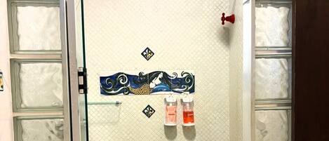 A shower area with frosted glass doors, a tiled wall with a decorative design, and two soap dispensers.