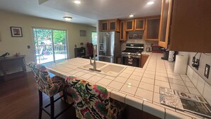 A kitchen with a large island, wooden cabinets, and a view to the outside.