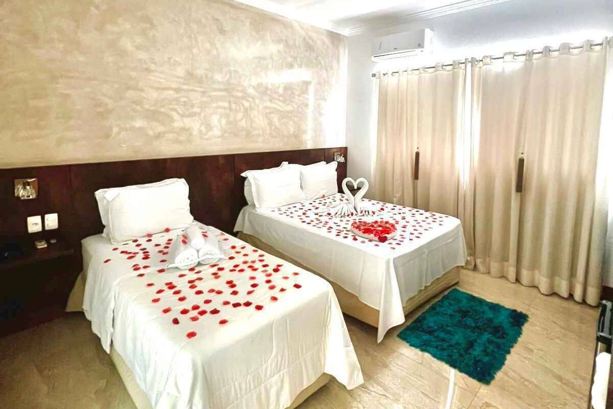 Ein Hotelzimmer mit zwei Betten, jedes geschmückt mit Rosenblättern und einer herzförmigen Dekoration.