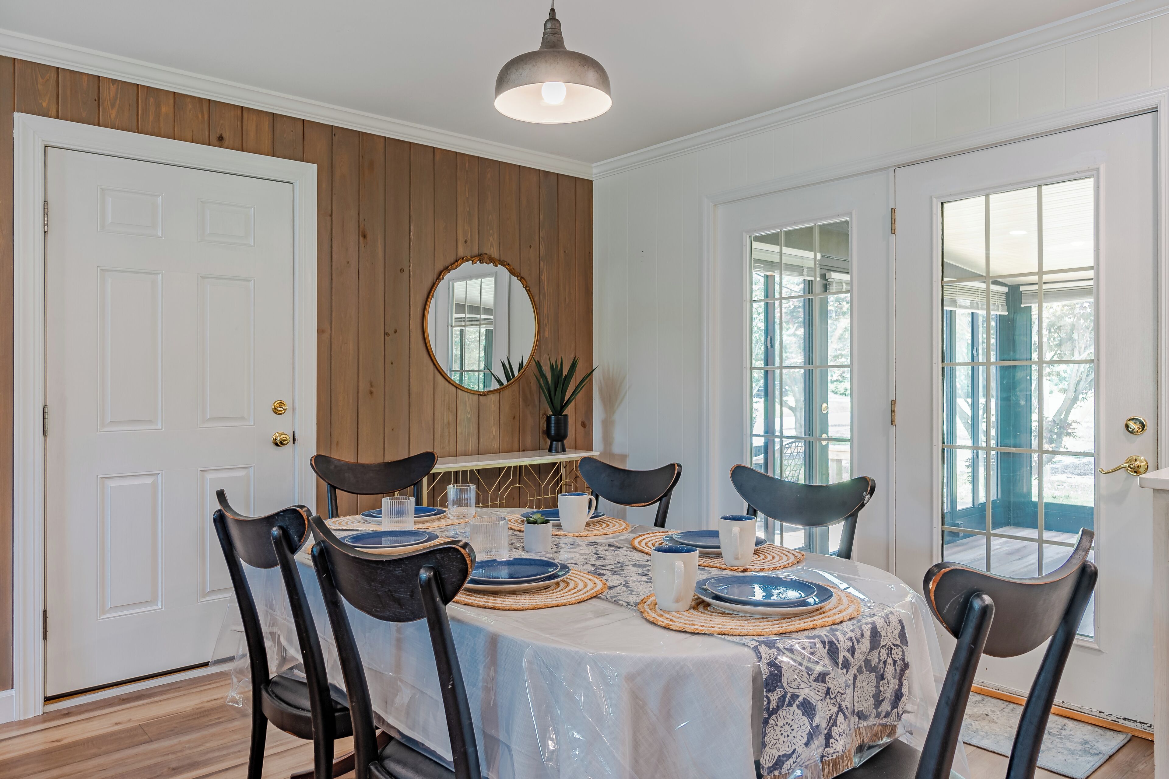 Une salle à manger avec une table ronde dressée pour six personnes, entourée de six chaises.