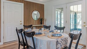 Une salle à manger avec une table ronde dressée pour six personnes, entourée de six chaises.