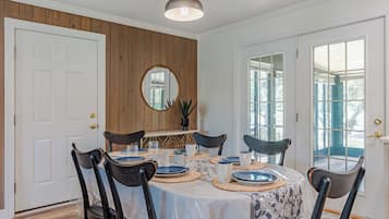 Une salle à manger avec une table ronde dressée pour six personnes, entourée de six chaises.