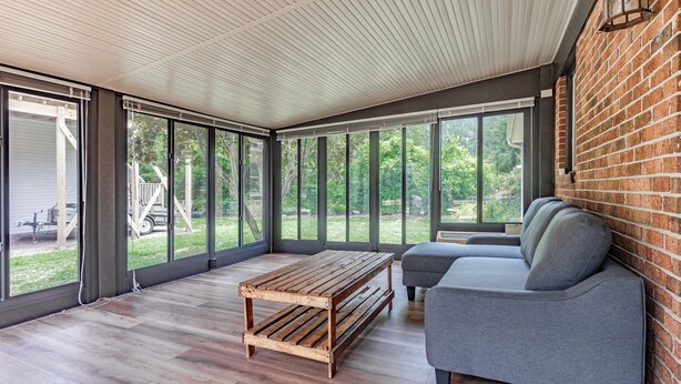 Une pièce spacieuse avec de grandes fenêtres, une table basse en bois et un canapé gris.