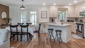 Une cuisine moderne avec des meubles blancs, un îlot central et un coin repas comprenant une table et des chaises.