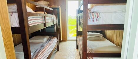 A wooden cabin with bunk beds, a ceiling fan, and a door leading outside.