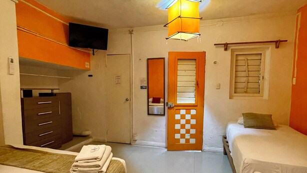 Een hotelkamer met twee bedden, een kledingkast, een televisie en een zwart-wit deur.