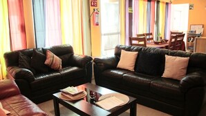 A room with two leather sofas, a coffee table, and a dining area with chairs and a table. - Full house for 14 guests. A/C, TV, Wi-Fi, kitchen, dining and living room. Near beaches and downtown (Centro Isla Mujeres)