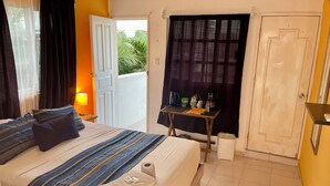 Ein Hotelzimmer mit Bett, Nachttisch, Tisch mit Toilette und Blick auf Grünfläche draußen.