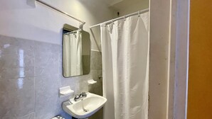 Ein Badezimmer mit einem weißen Waschbecken, einem Spiegel und einer Duschvorhang.