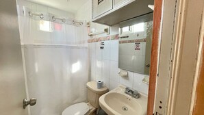 A small bathroom with a toilet, sink, and shower curtain. - Studio for 3 guests. A/C, Wi-Fi, TV, kitchen, balcony. Near ferry and beach. (Centro Isla Mujeres)