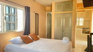 A bedroom with a bed, a window, and a kitchenette. - Studio for 3 guests. A/C, Wi-Fi, TV, kitchen, balcony. Near ferry and beach. (Centro Isla Mujeres)