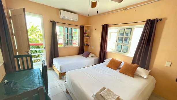 A hotel room with two beds, a desk, and a chair. - Studio for 3 guests. A/C, Wi-Fi, TV, kitchen, balcony. Near ferry and beach. (Centro Isla Mujeres)