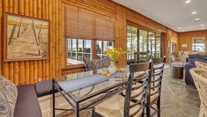 A modern interior with a wooden wall paneling, a dining area with a glass table, and a seating arrangement with sofas and chairs. - Horsepen Cottage on the Water !!!! (Tybee Island)