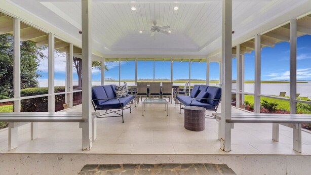 A covered patio with two blue sofas, a glass-top table, and a ceiling fan. - Horsepen Cottage on the Water !!!! (Tybee Island)