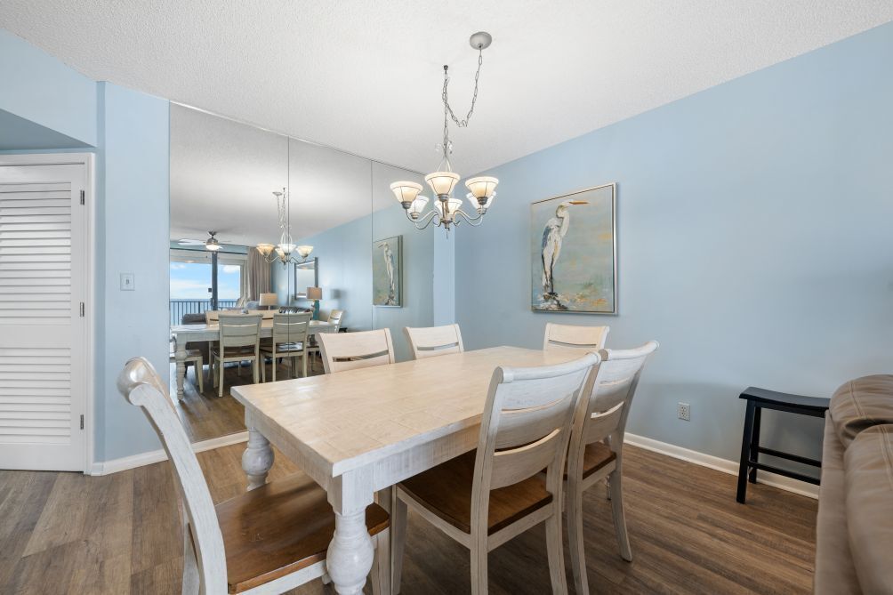 A dining area with a wooden table and chairs, a chandelier, and artwork on the walls.