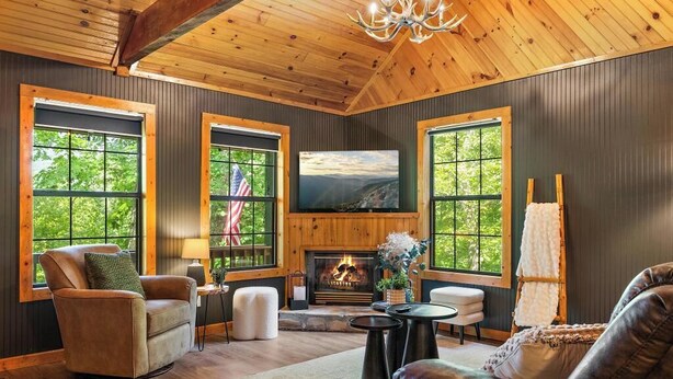 Un salon chaleureux avec une cheminée, des canapés en cuir et de grandes fenêtres à cadres en bois.