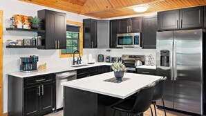 Une cuisine moderne avec des meubles de couleur sombre, des appareils électroménagers en acier inoxydable et un îlot central.