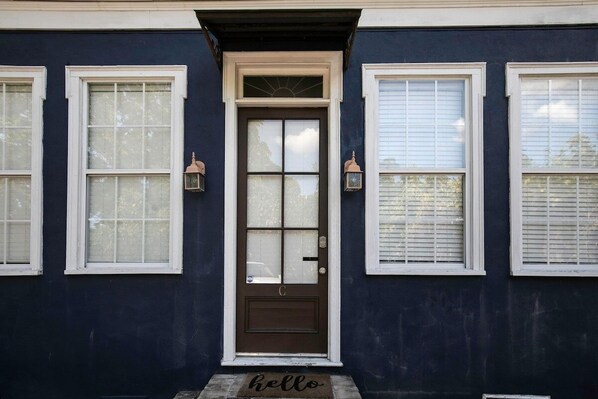 A dark blue house with a brown front door, white-framed windows, and two lantern-style lights on either side of the door.