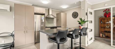 A modern kitchen with a central island, stainless steel appliances, and a dining area with bar stools.